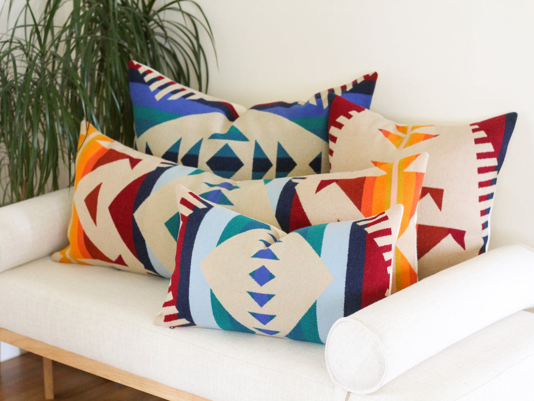 Four pillows with in the bold, colorful southwestern Los Lunas pattern from Pendleton, sitting on a white bench