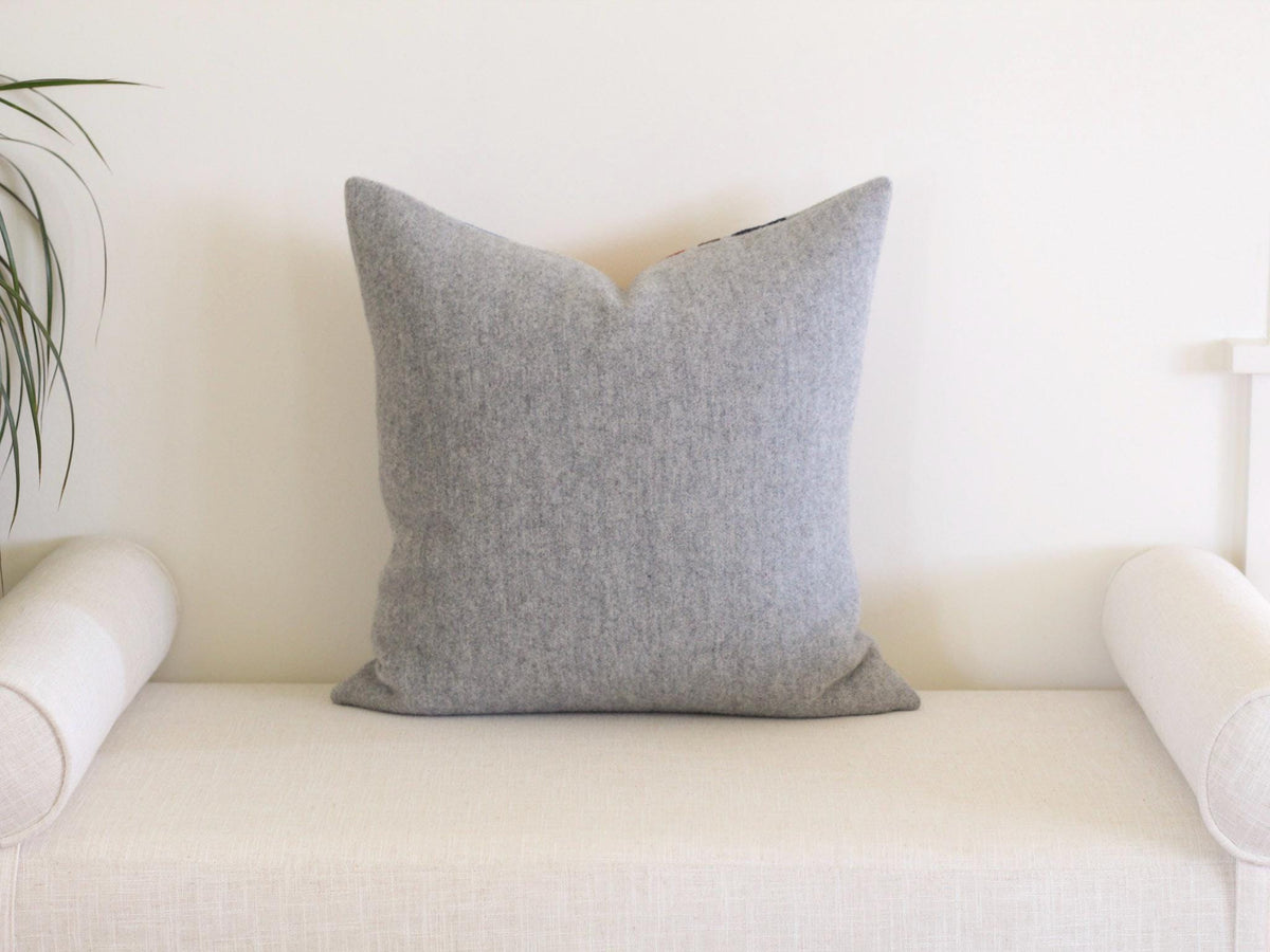 The back of a decorative throw pillow in solid light gray wool. 