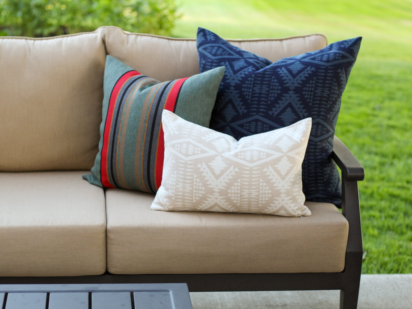 Beige outdoor sofa with colorful outdoor pillows on a grassy background