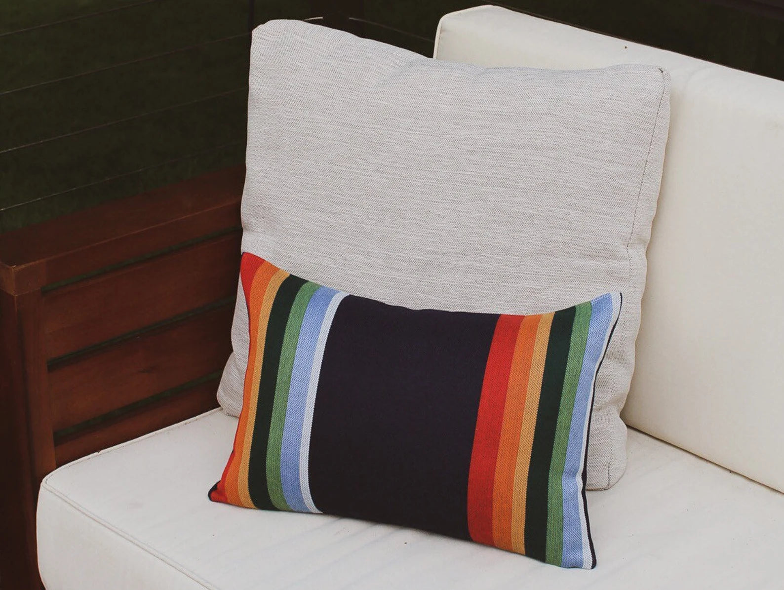 Pillow with a colorful striped pattern on a white couch.