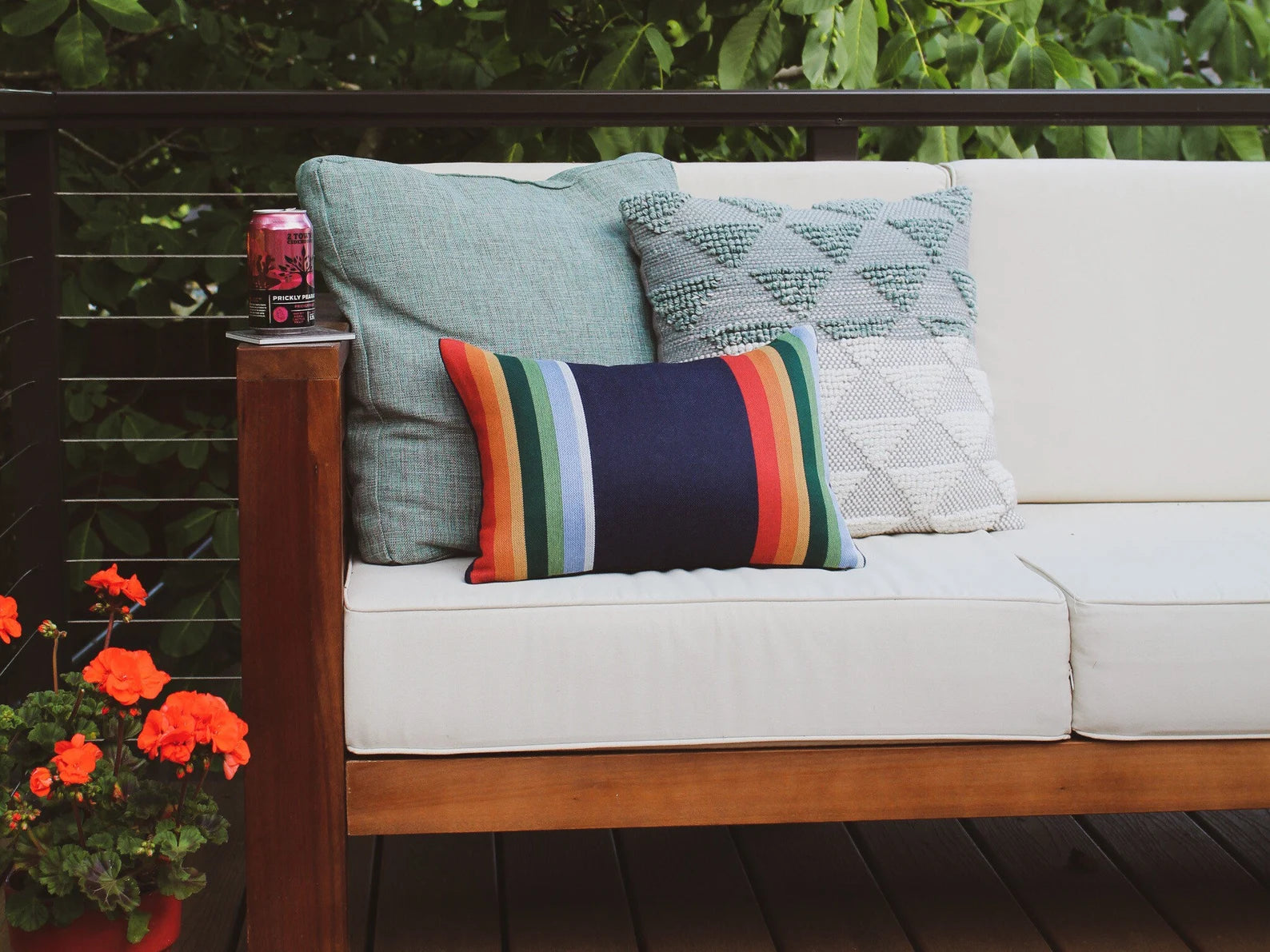 White outdoor sofa with colorful and patterned cushions on a wooden deck.