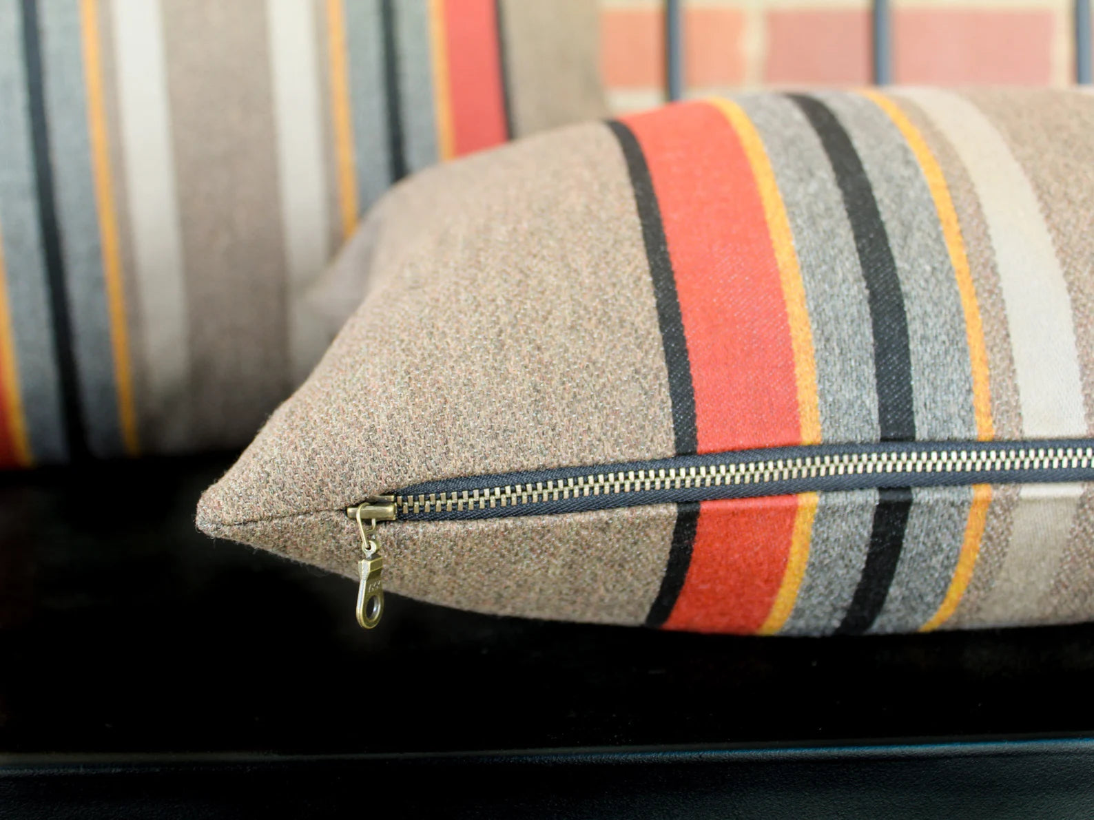 Outdoor pillow in the Yakima Park Umber stripe with a zipper on a black metal bench
