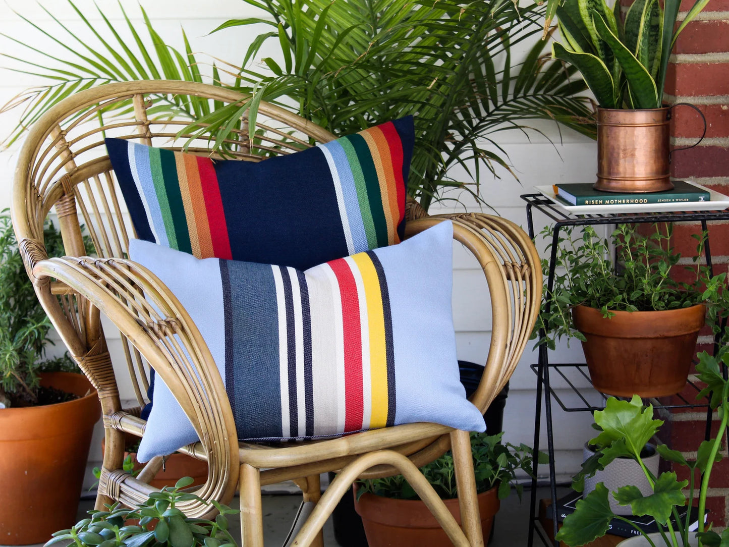 Wicker chair with colorful striped outdoor pillow covers in a garden setting