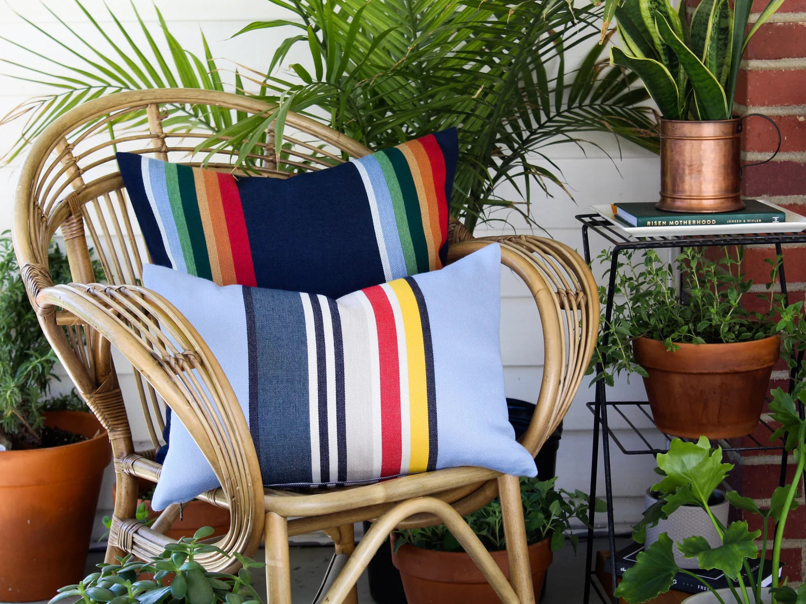 Wicker chair with colorful striped outdoor pillow covers in a garden setting
