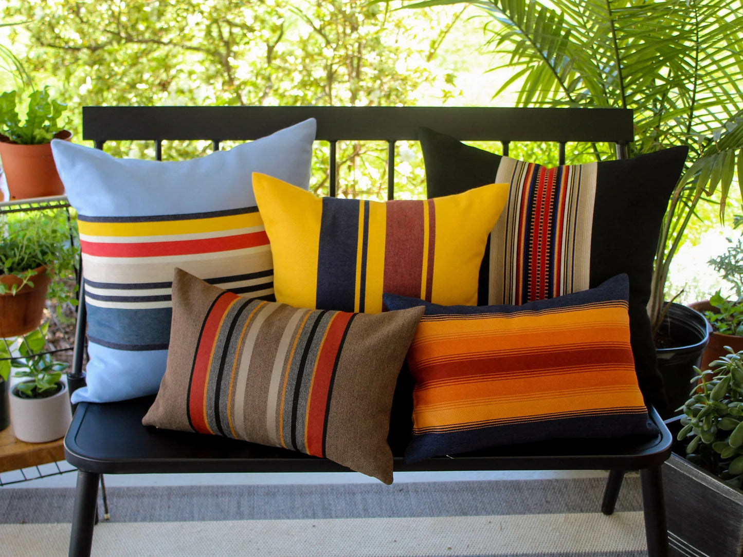 Colorful striped outdoor pillows on a bench with a garden background