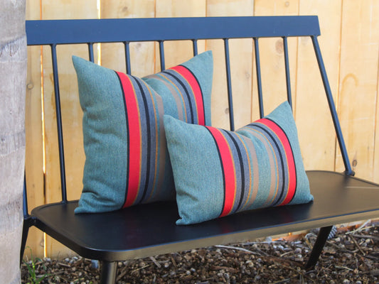 Black bench with outdoor pillow covers in Yakima Park Heather against a wooden fence.