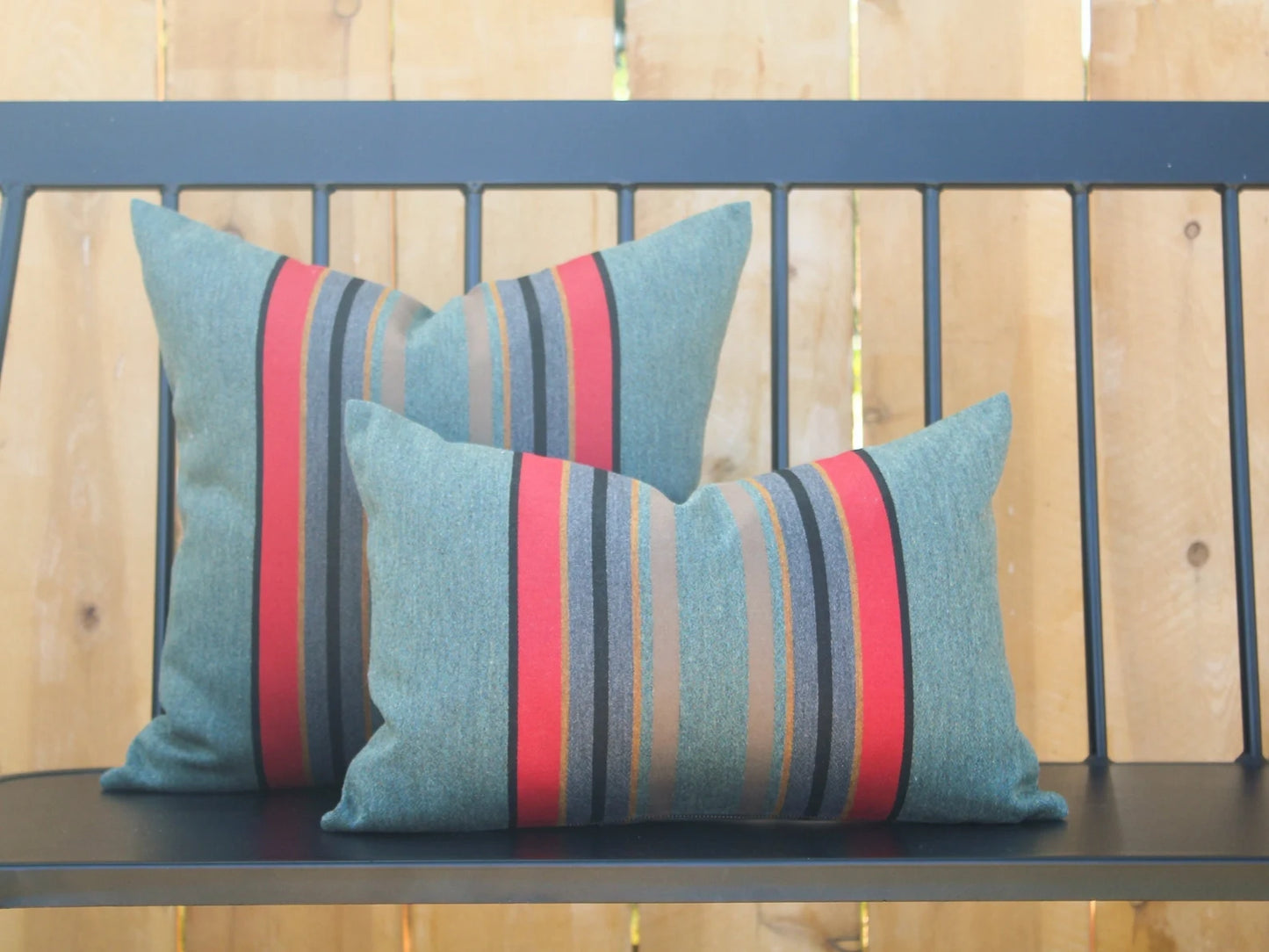 Two striped pillows in Yakima Park Heather on a bench with a wooden background
