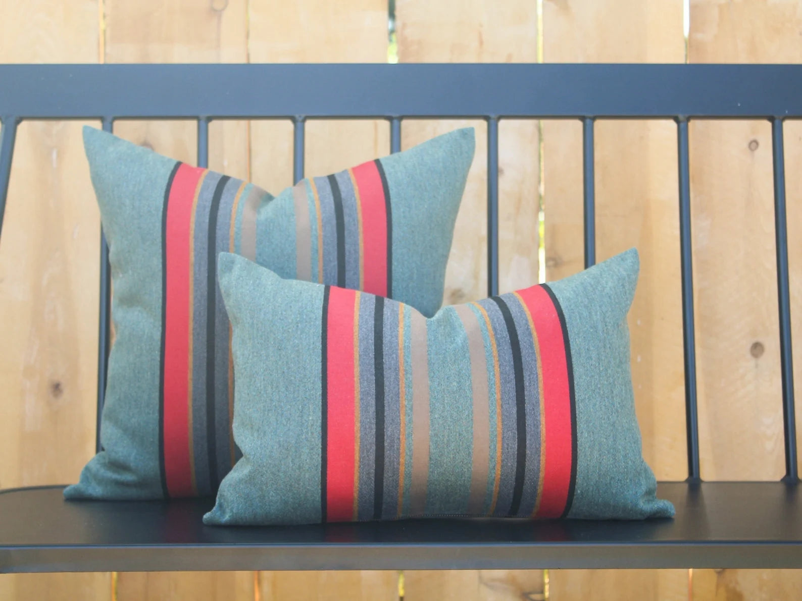 Two striped pillows in Yakima Park Heather on a bench with a wooden background