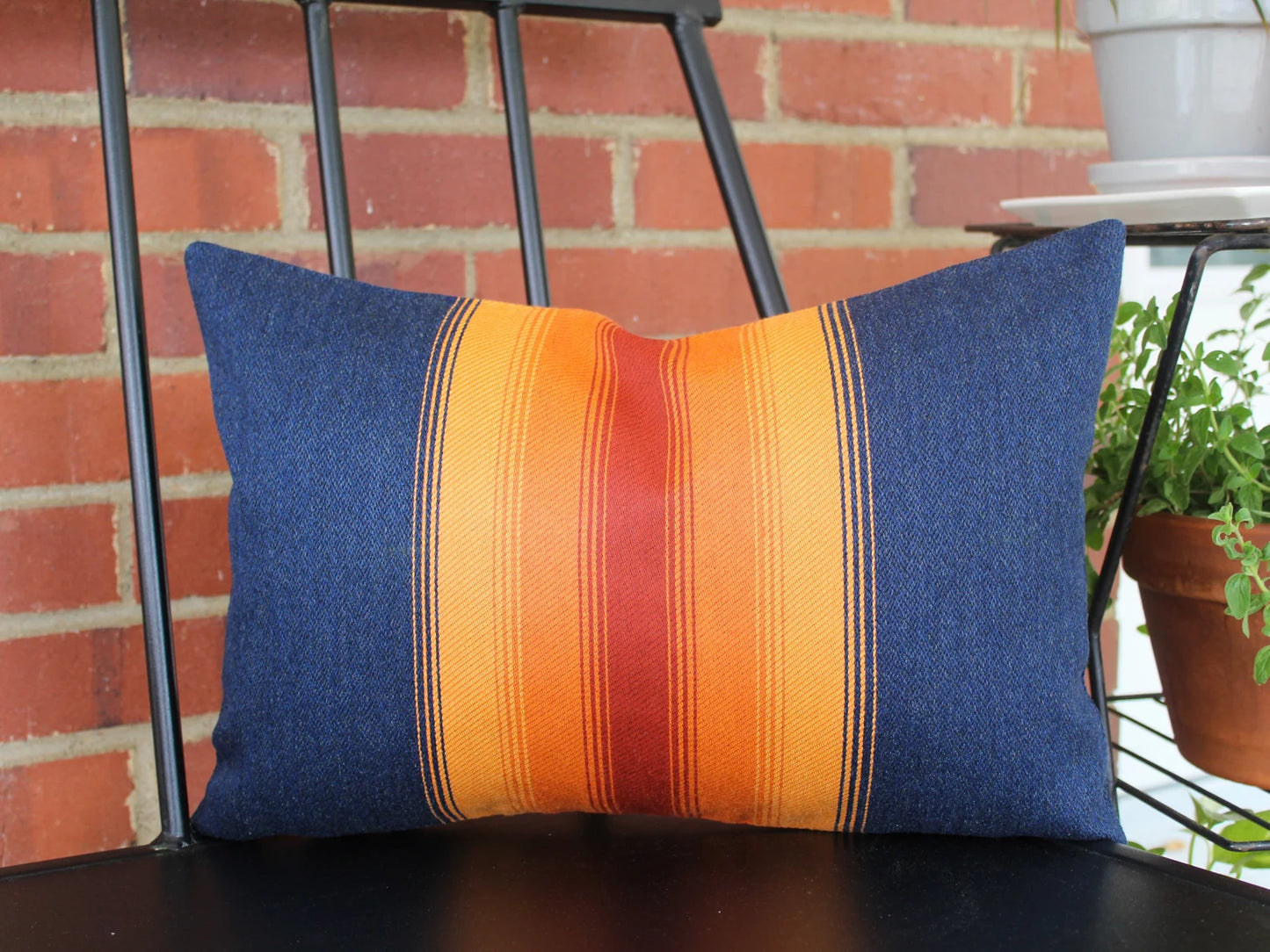 Colorful striped pillow on a chair with a brick wall background