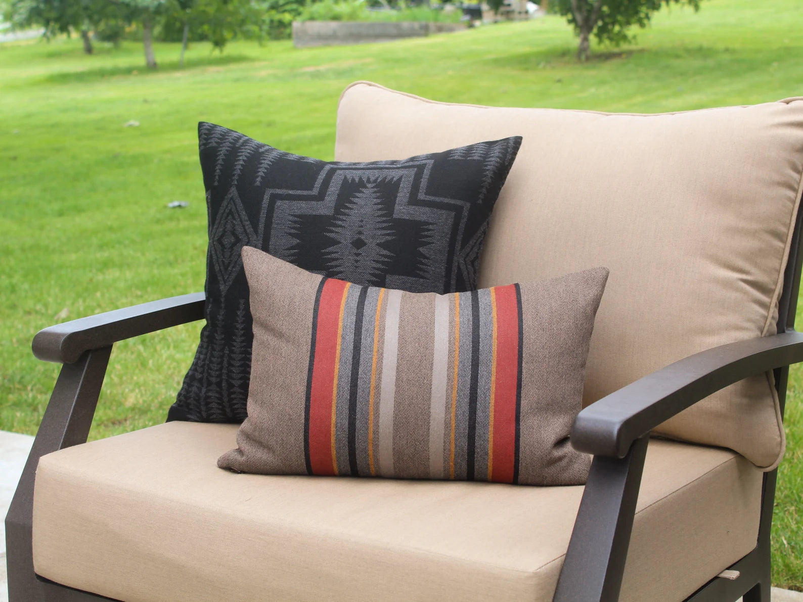 Beige outdoor chair with outdoor pillows on a grassy background
