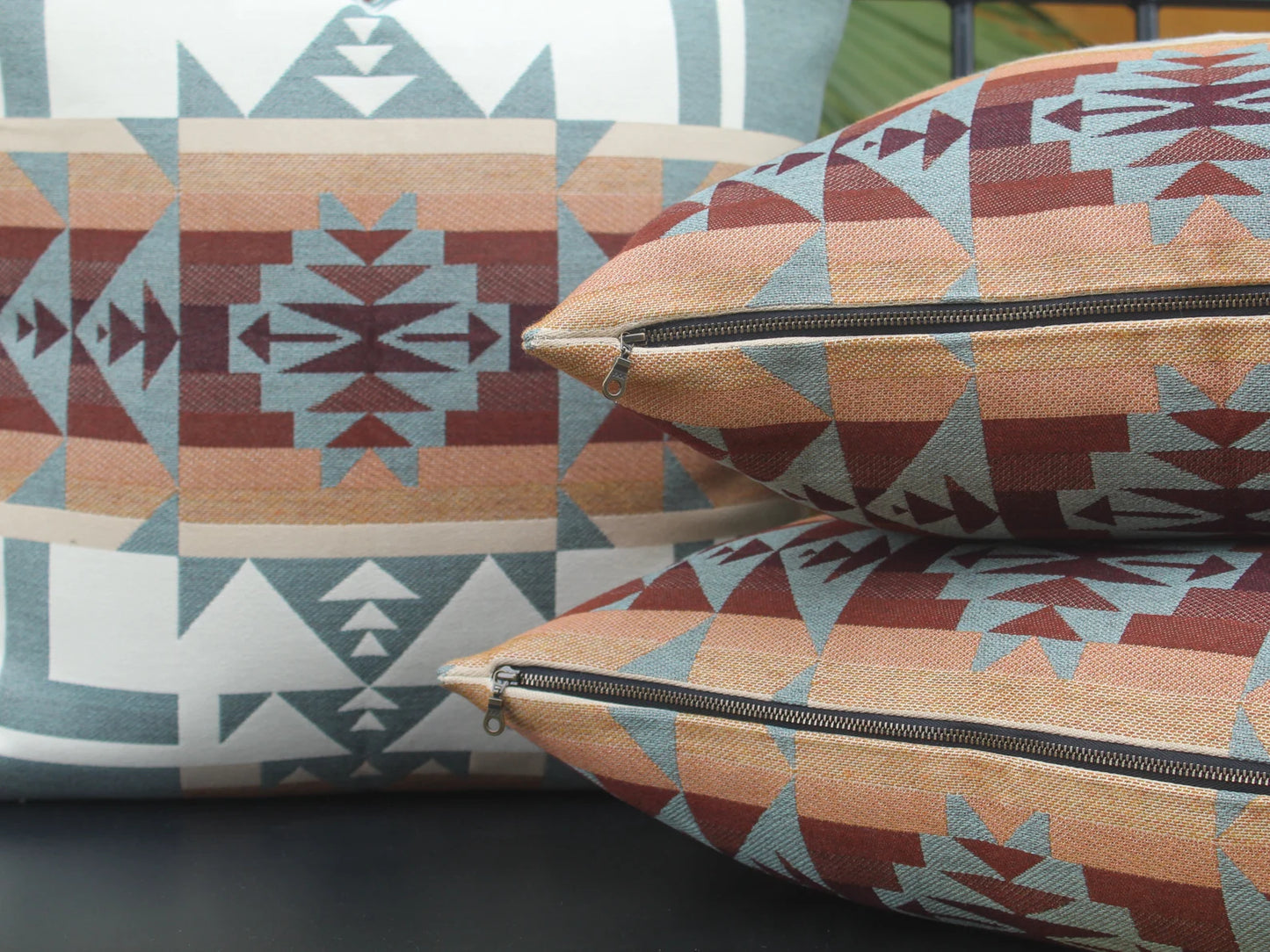 Close up of exposed metal zipper on outdoor pillows in the blue, brown, and white southwestern Chief Joseph pattern on a bench with a natural background