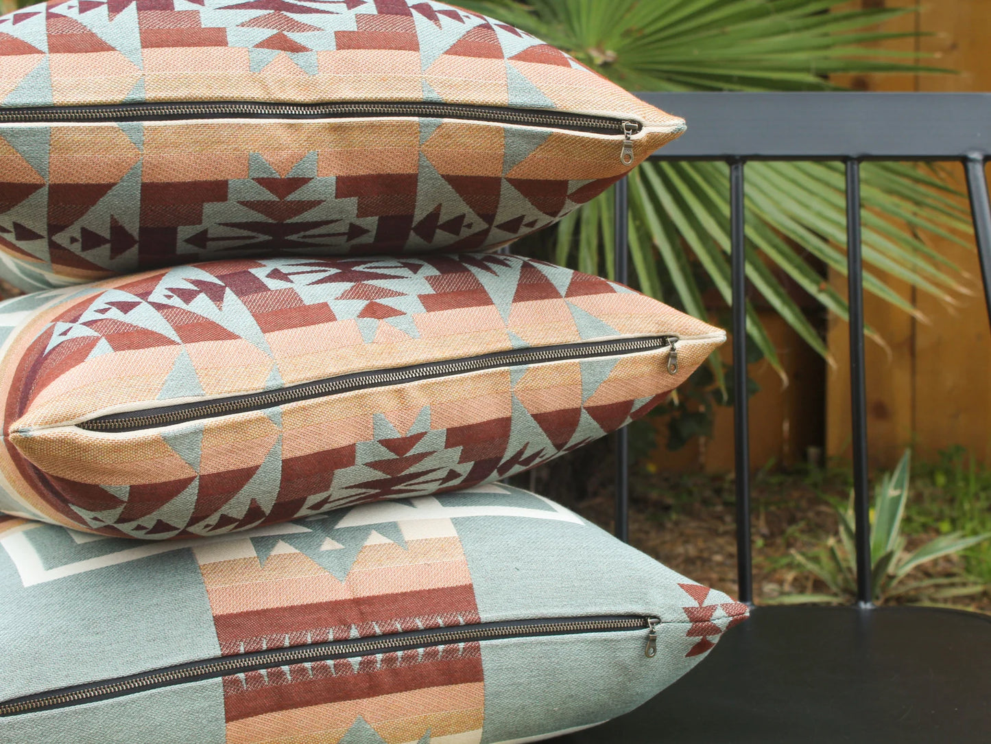 Close up of exposed metal zipper on outdoor pillows in the blue, brown, and white southwestern Chief Joseph pattern on a bench with a natural background