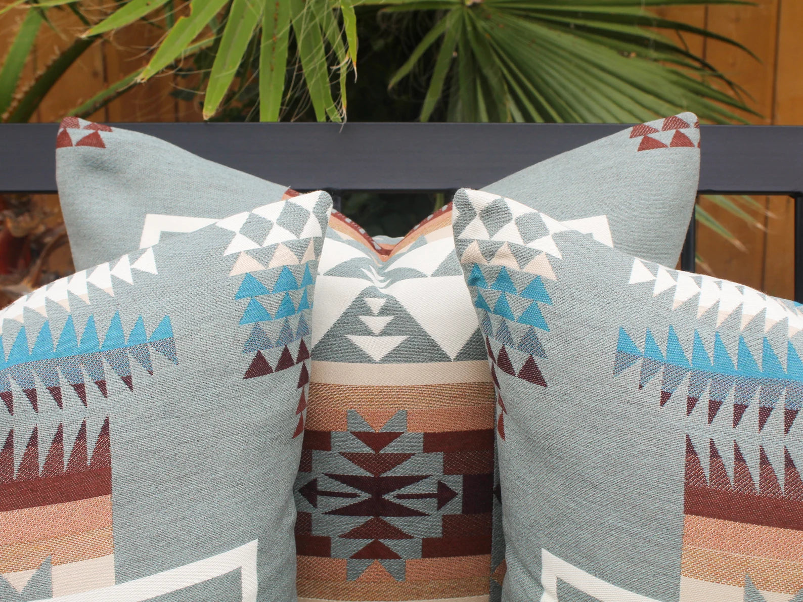 Close up of outdoor pillows in the blue, brown, and white southwestern Chief Joseph pattern on a bench with a natural background.