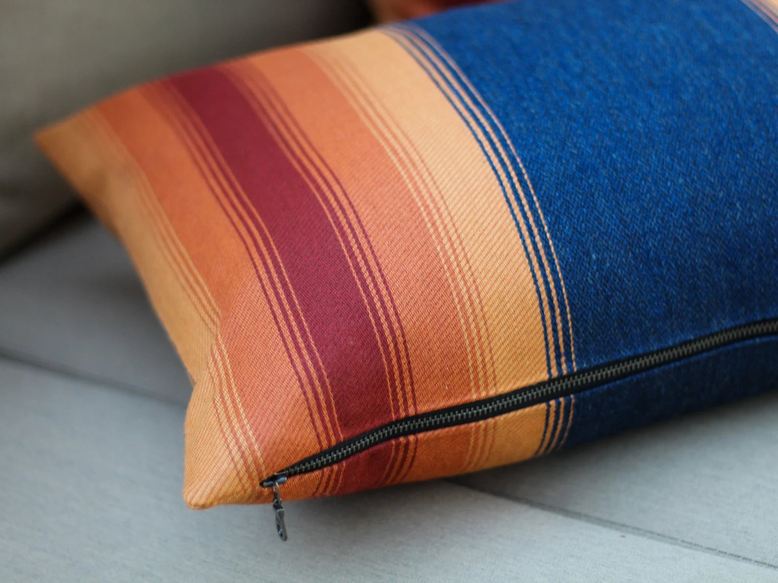 Colorful striped pillow with a zipper on a gray surface