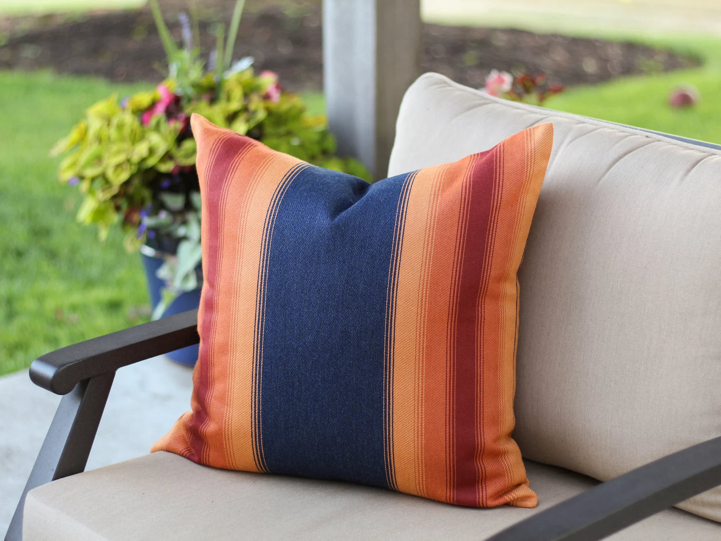 Striped outdoor pillow on a chair with a garden background