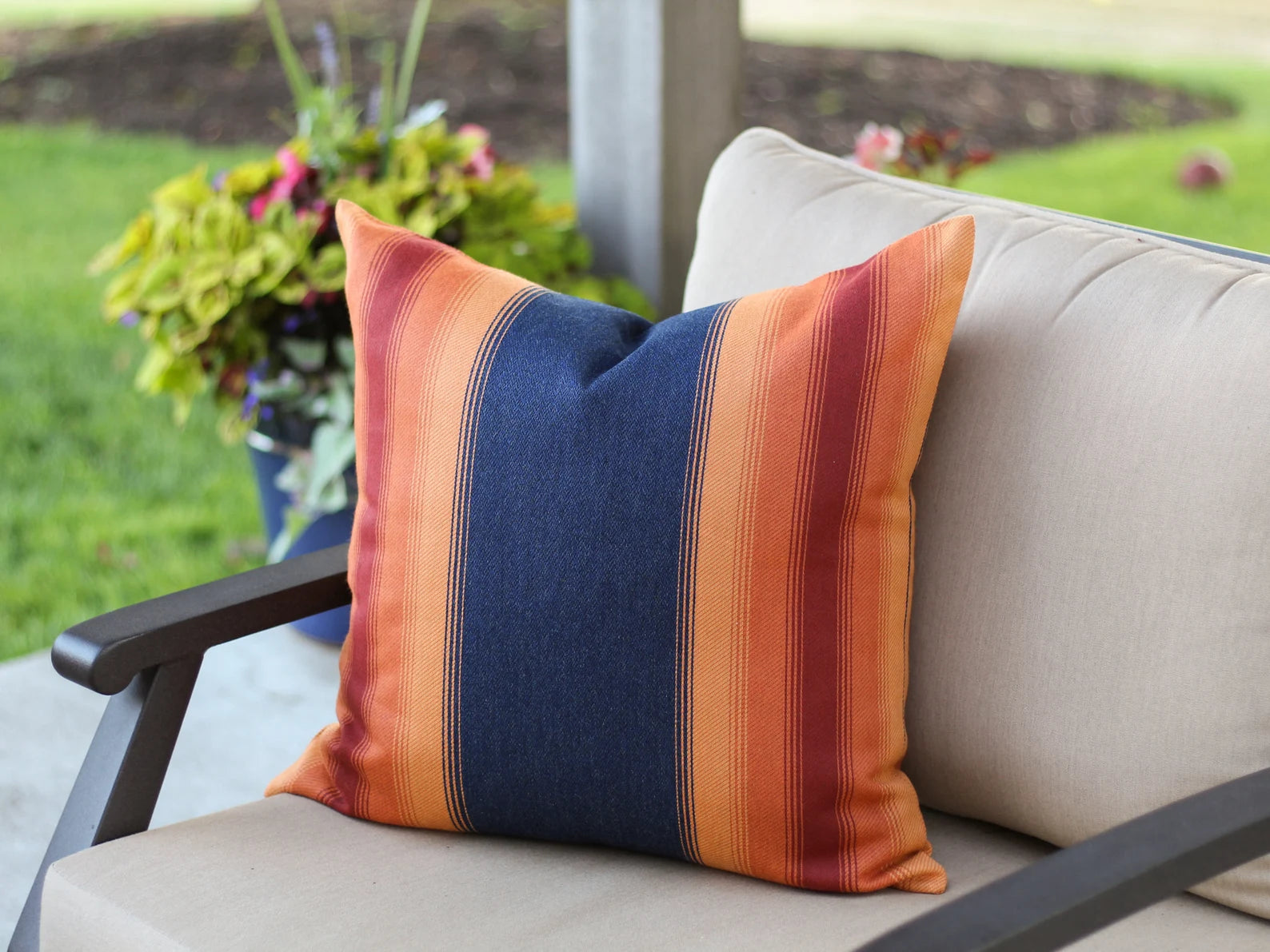 Striped outdoor pillow on a chair with a garden background