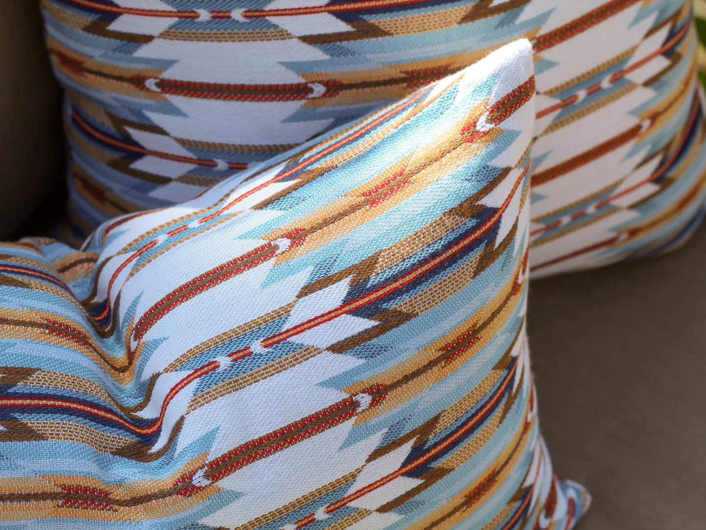 Close-up of outdoor pillows in the geometric Wyeth Trail Sunset pattern on a neutral background