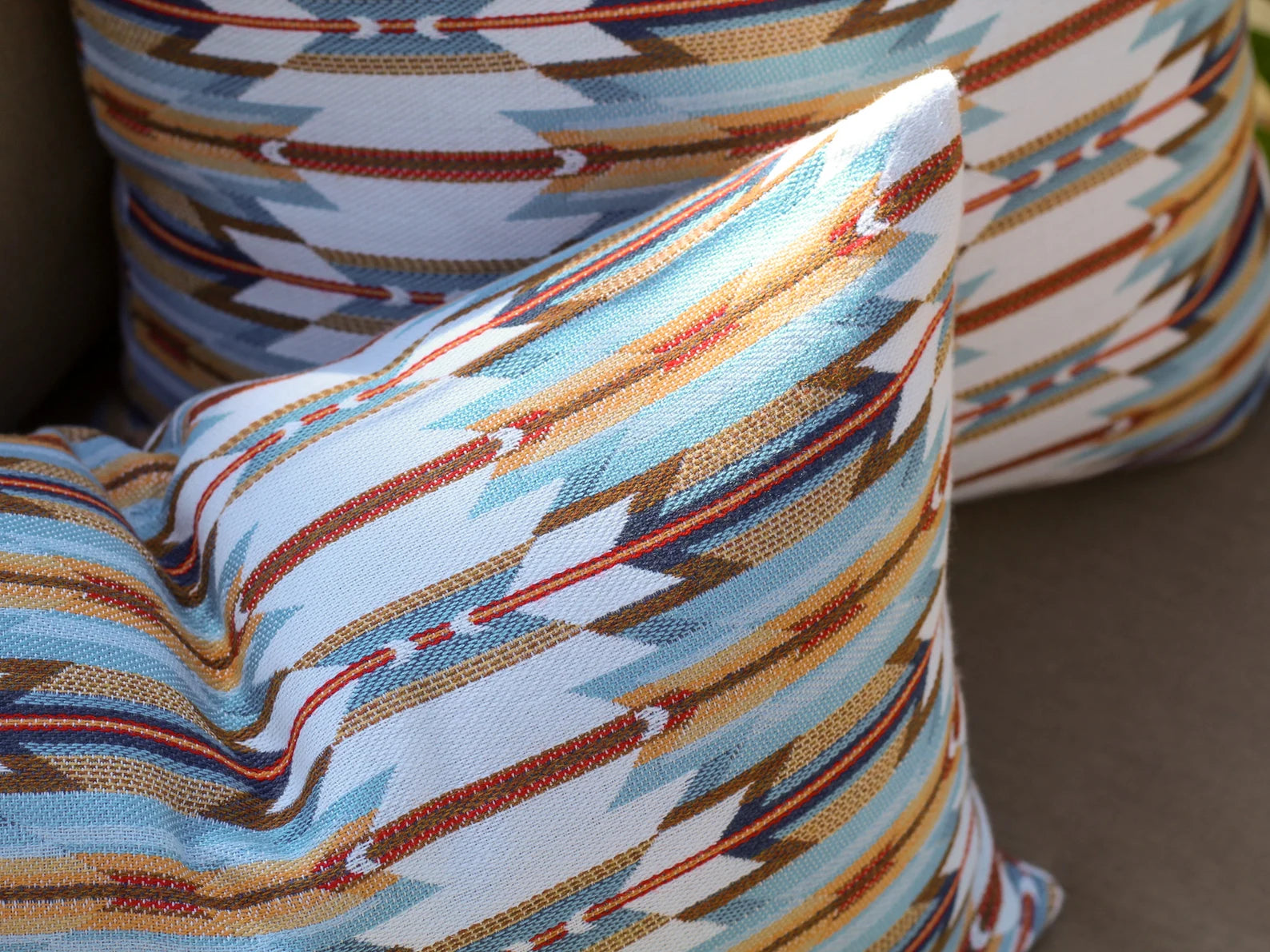 Close-up of outdoor pillows in the geometric Wyeth Trail Sunset pattern on a neutral background