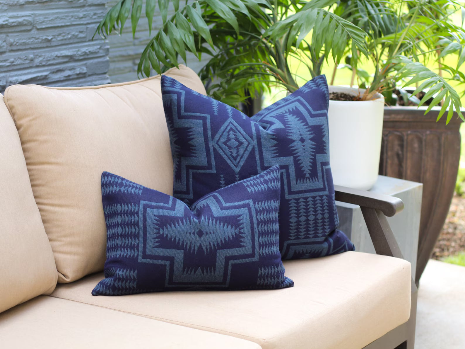 Beige outdoor sofa with outdoor pillows in the two-tone blue Harding Indigo pattern against an outdoor setting.