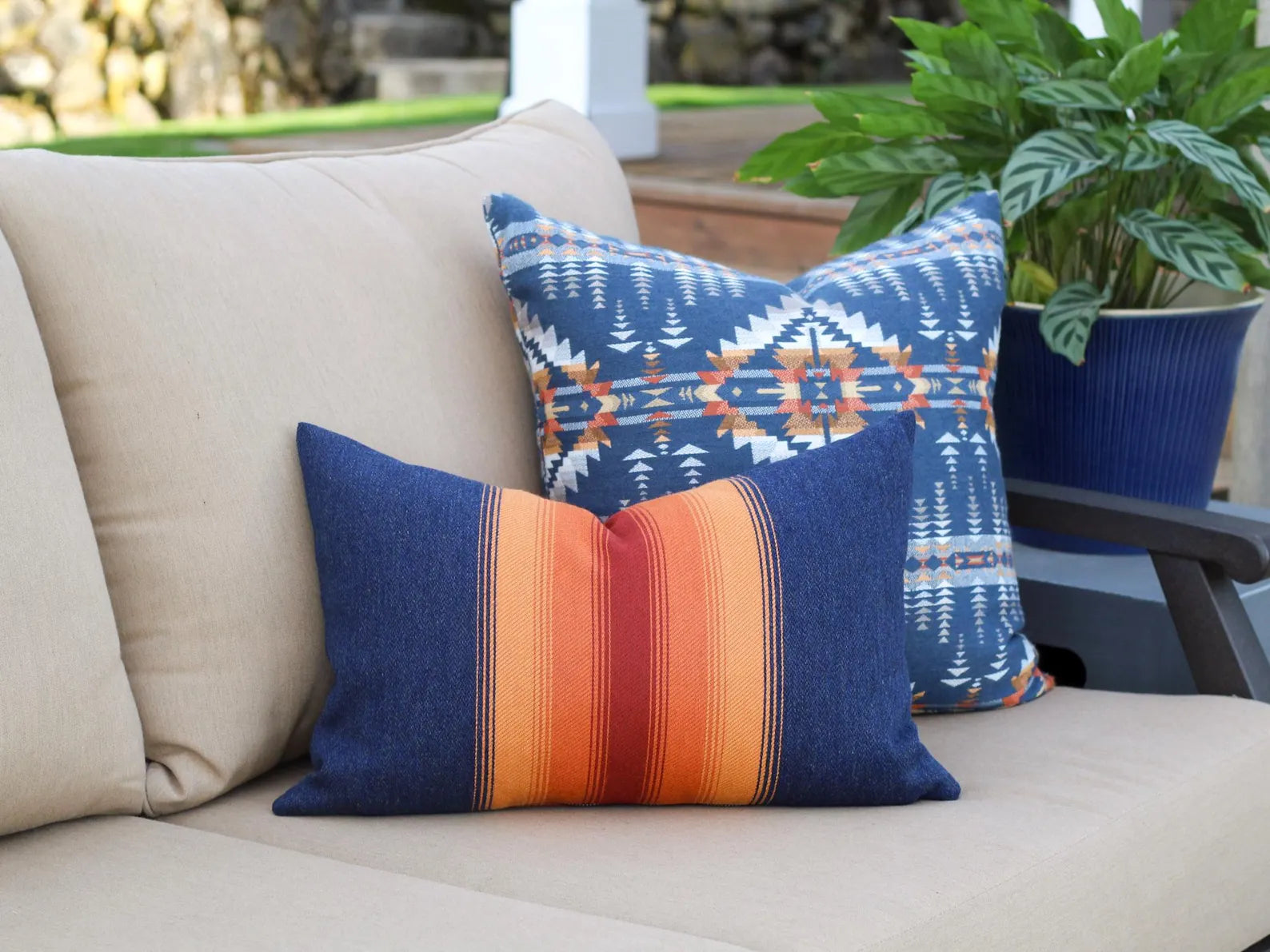 Colorful patterned pillows on a beige outdoor sofa with a blurred garden background