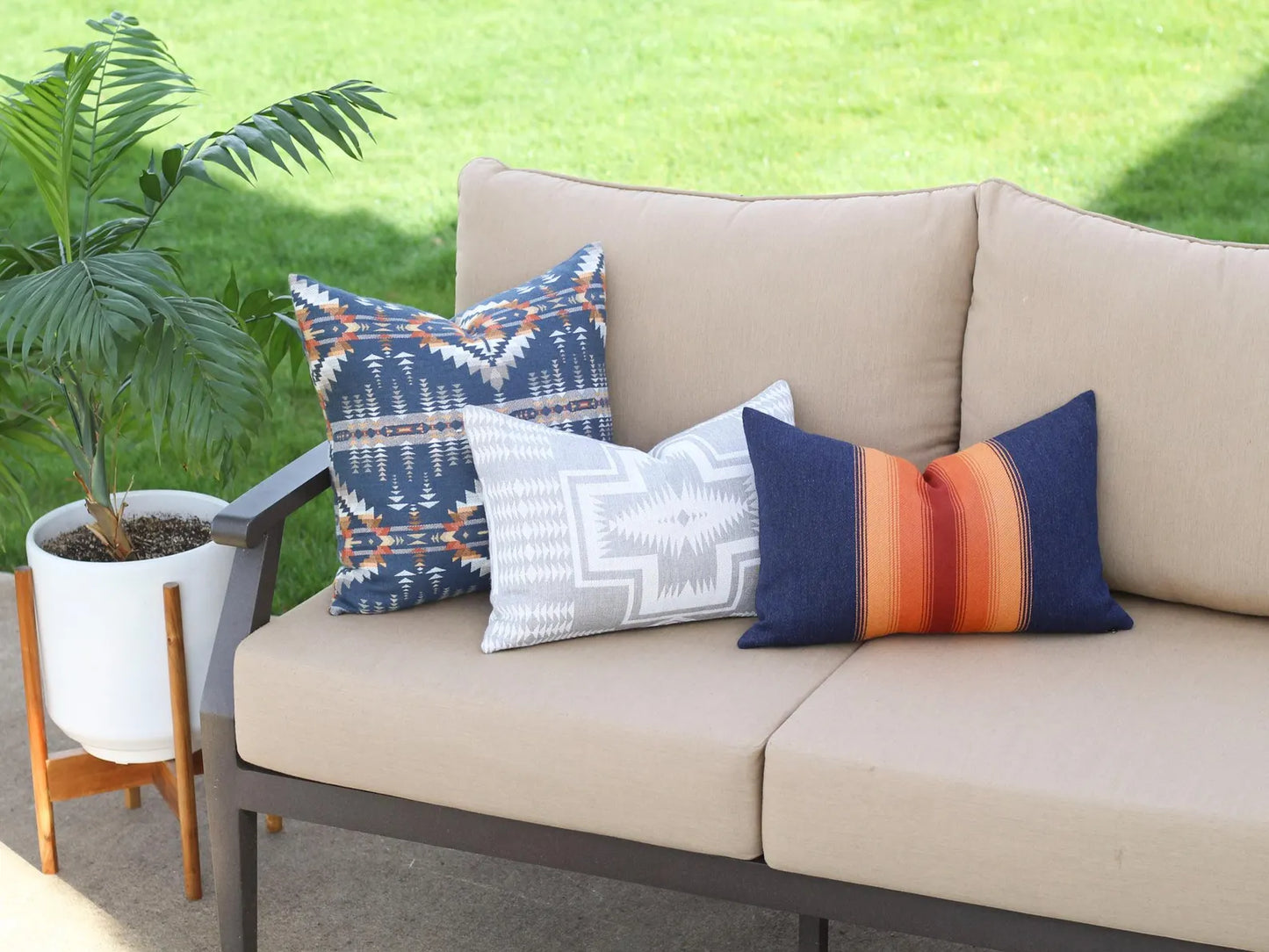 Beige outdoor sofa with colorful patterned cushions against a grassy background