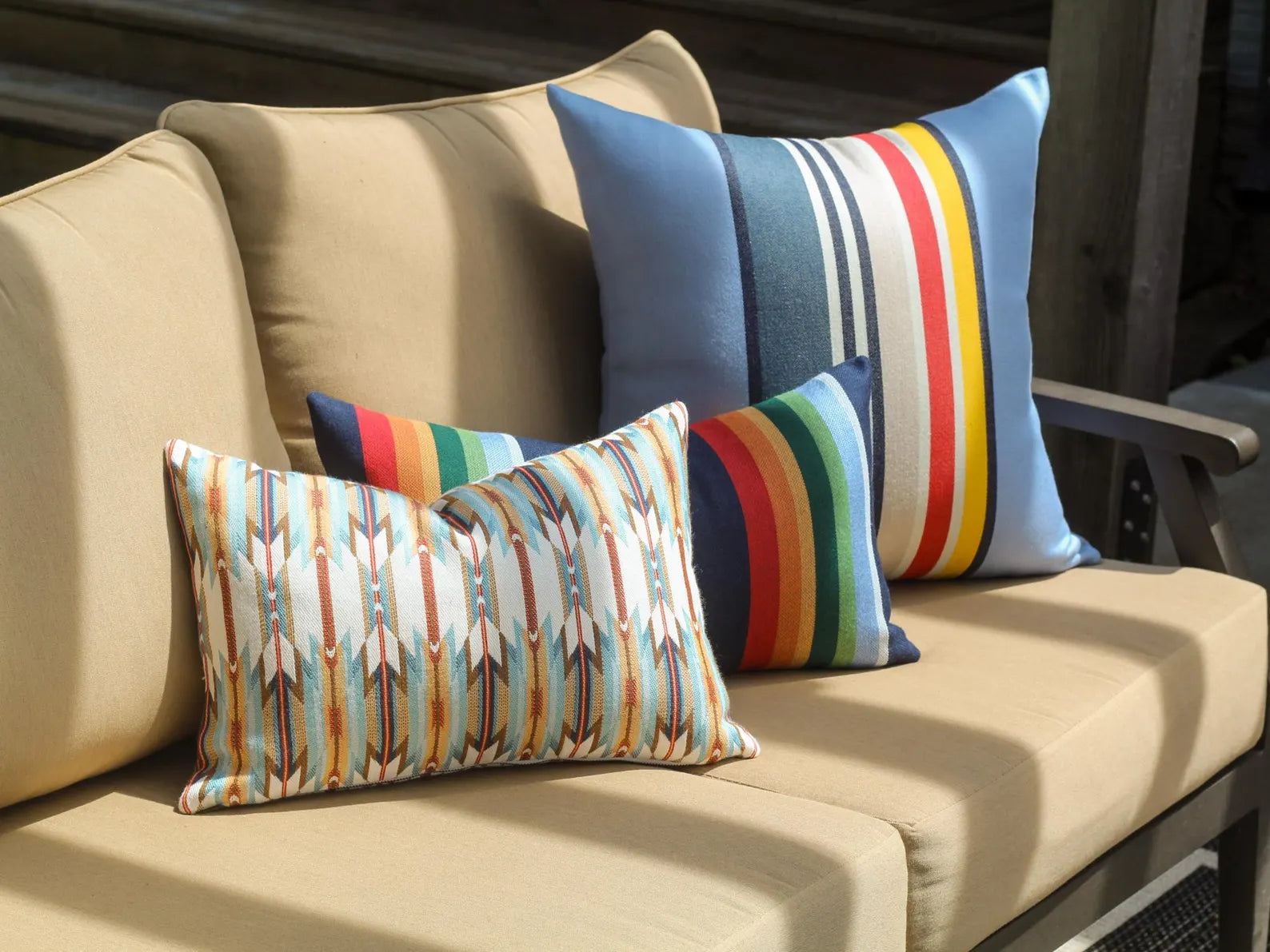 Colorful striped outdoor pillows on a beige outdoor sofa