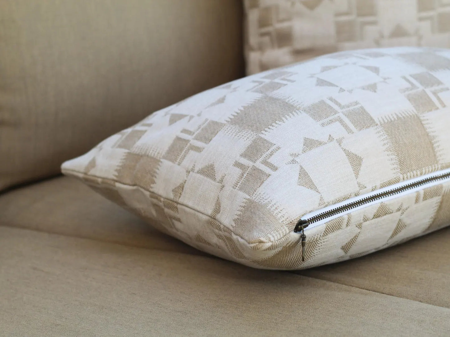 Close up of zipper on an outdoor pillow cover in the two-tone tan Silver Lake Dune pattern. This pattern has a Textural matelasse design.