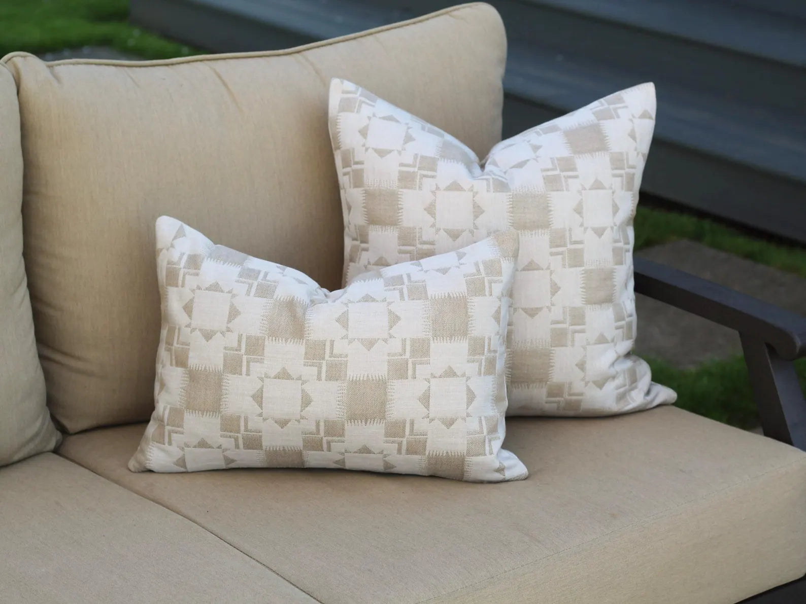 Beige outdoor sofa with two outdoor pillow covers in the two-tone tan Silver Lake Dune pattern. This pattern has a Textural matelasse design.