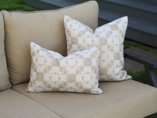 Beige outdoor sofa with two outdoor pillow covers in the two-tone tan Silver Lake Dune pattern. This pattern has a Textural matelasse design.