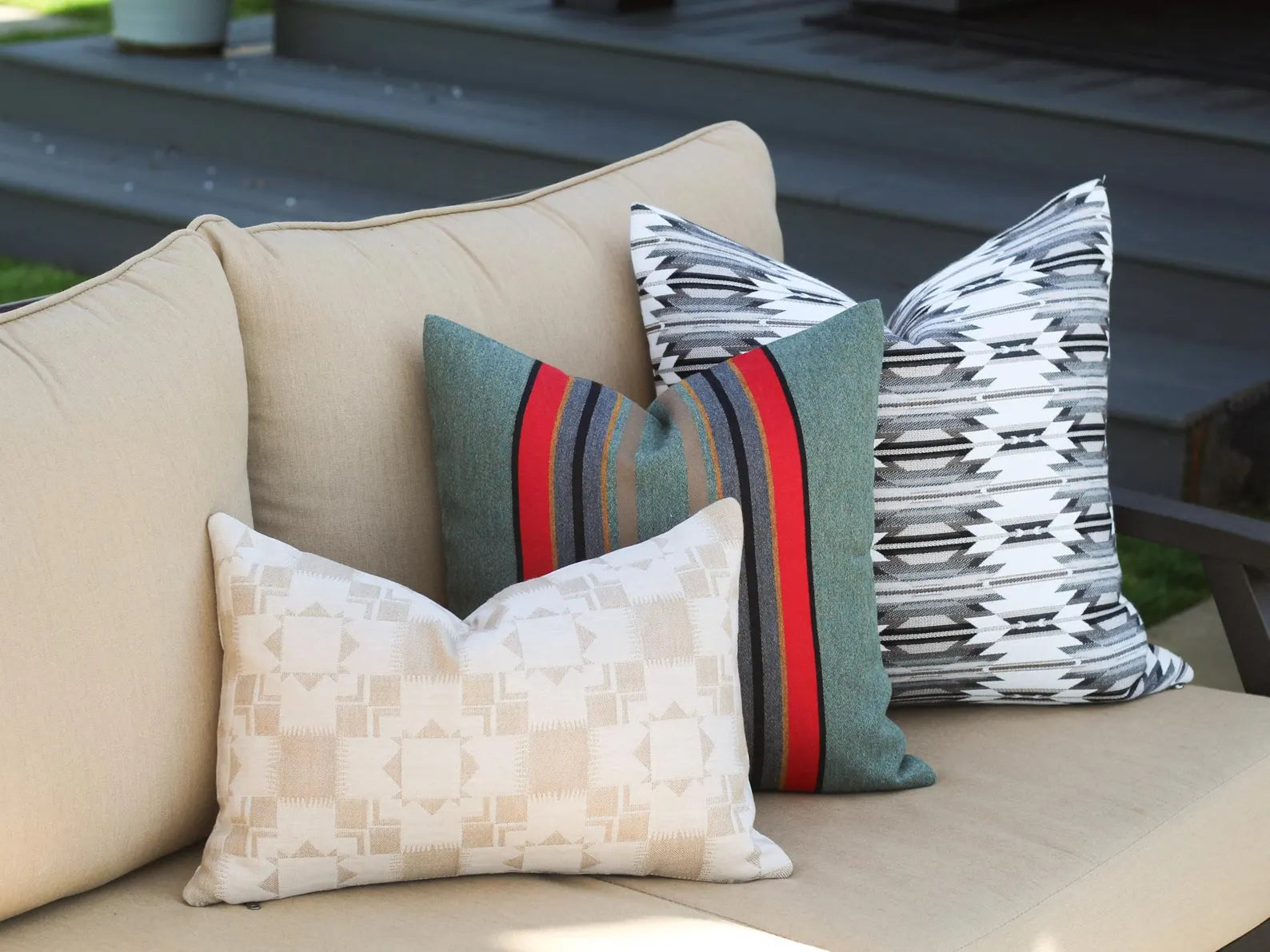 Outdoor pillows on a beige outdoor sofa with a wooden deck in the background