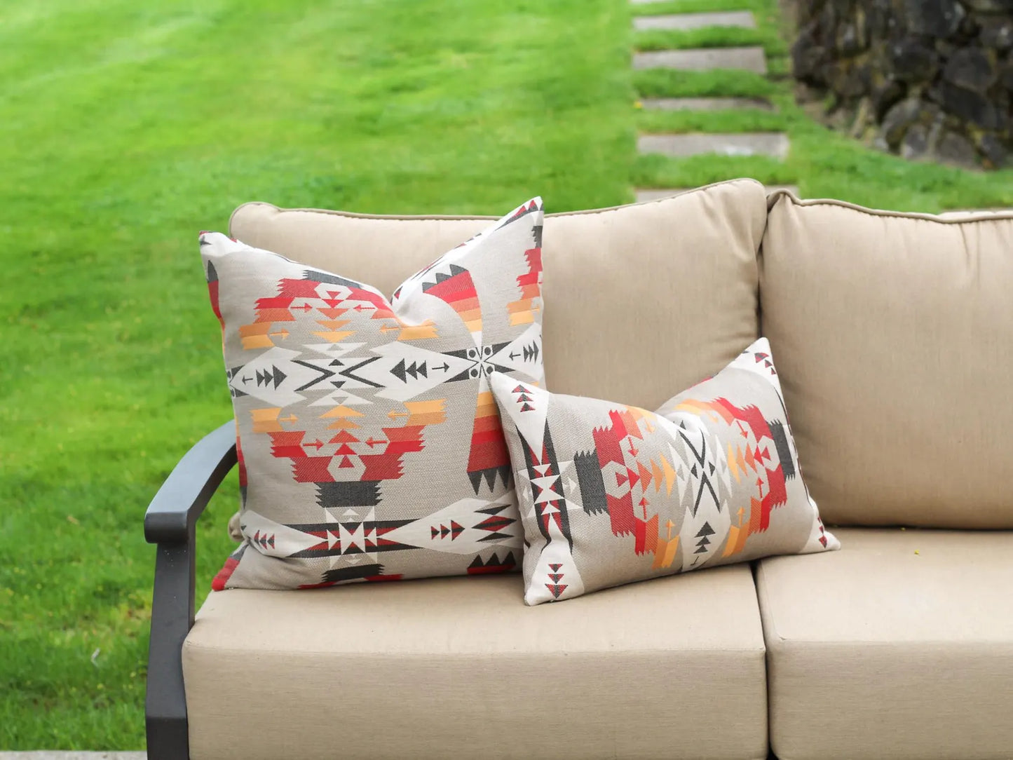 Decorative pillows in the Tucson Hawk pattern on a beige outdoor sofa against a grassy background.