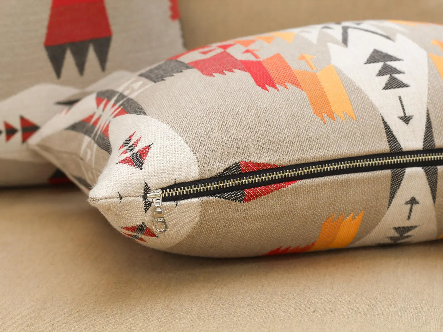 Close up of zipper on outdoor pillow coverin the Tucson Hawk pattern on a beige surface
