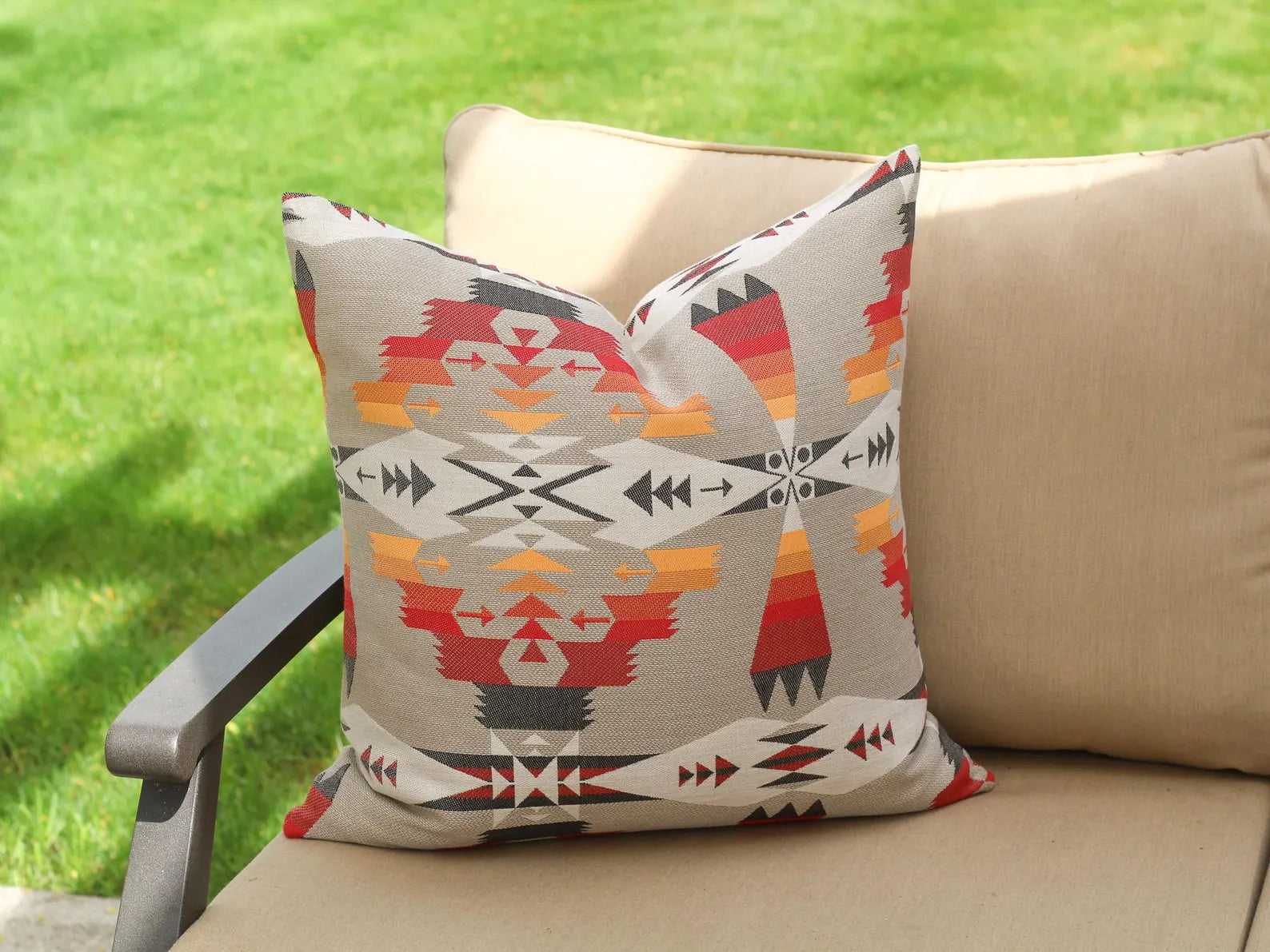 Decorative pillow in the Tucson Hawk pattern on a beige outdoor cushion against a grassy background