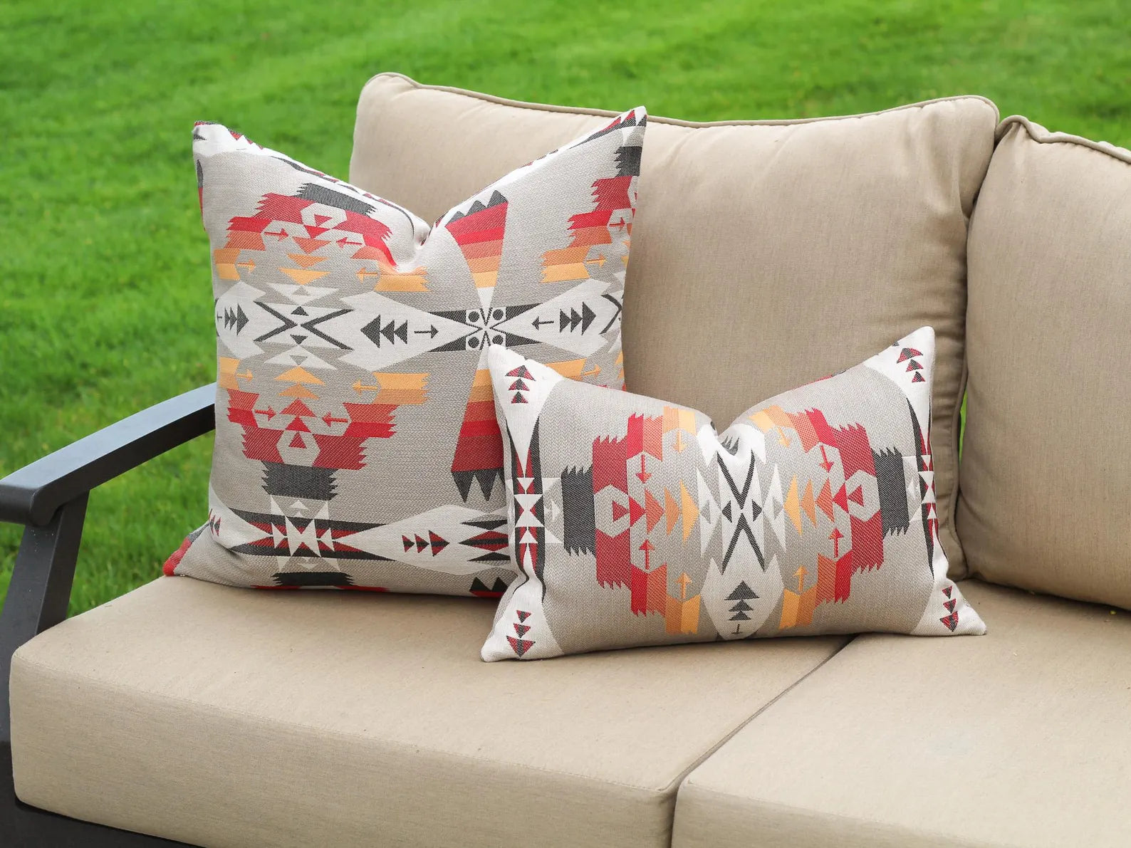 Decorative pillows in the Tucson Hawk pattern on a beige outdoor sofa against a grassy background