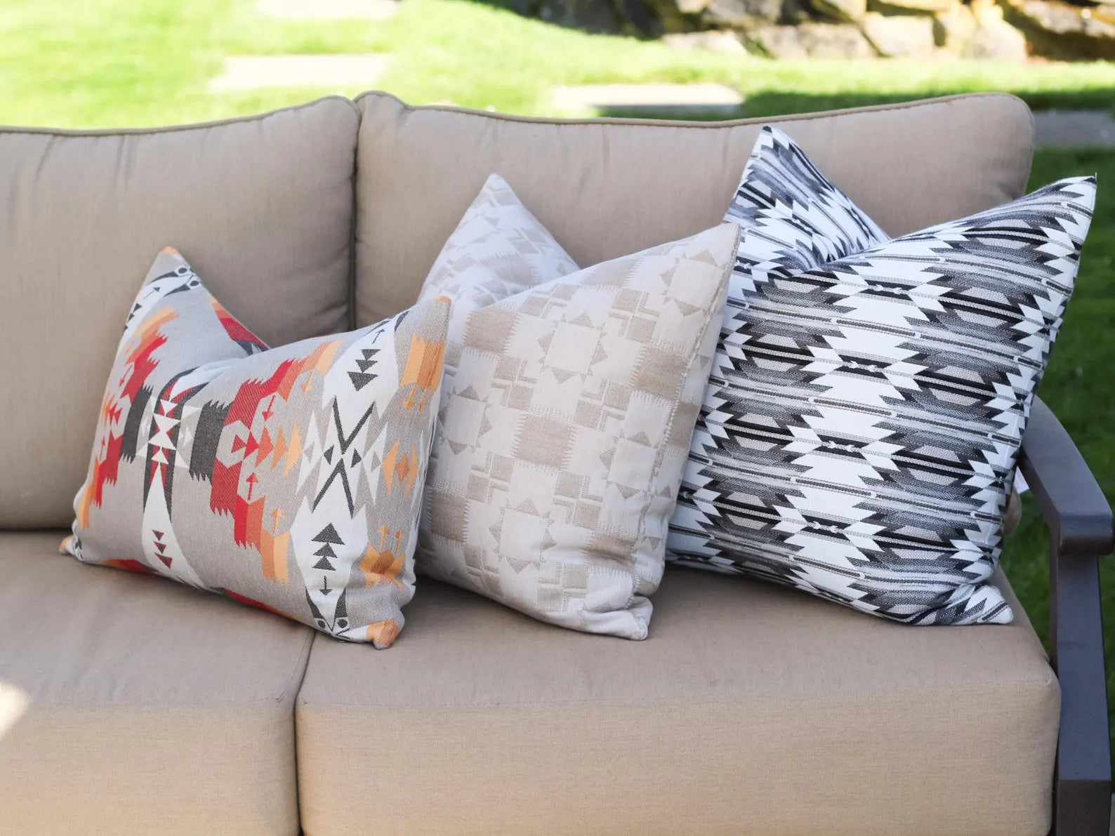 Outdoor pillows on a beige outdoor sofa with a grassy background