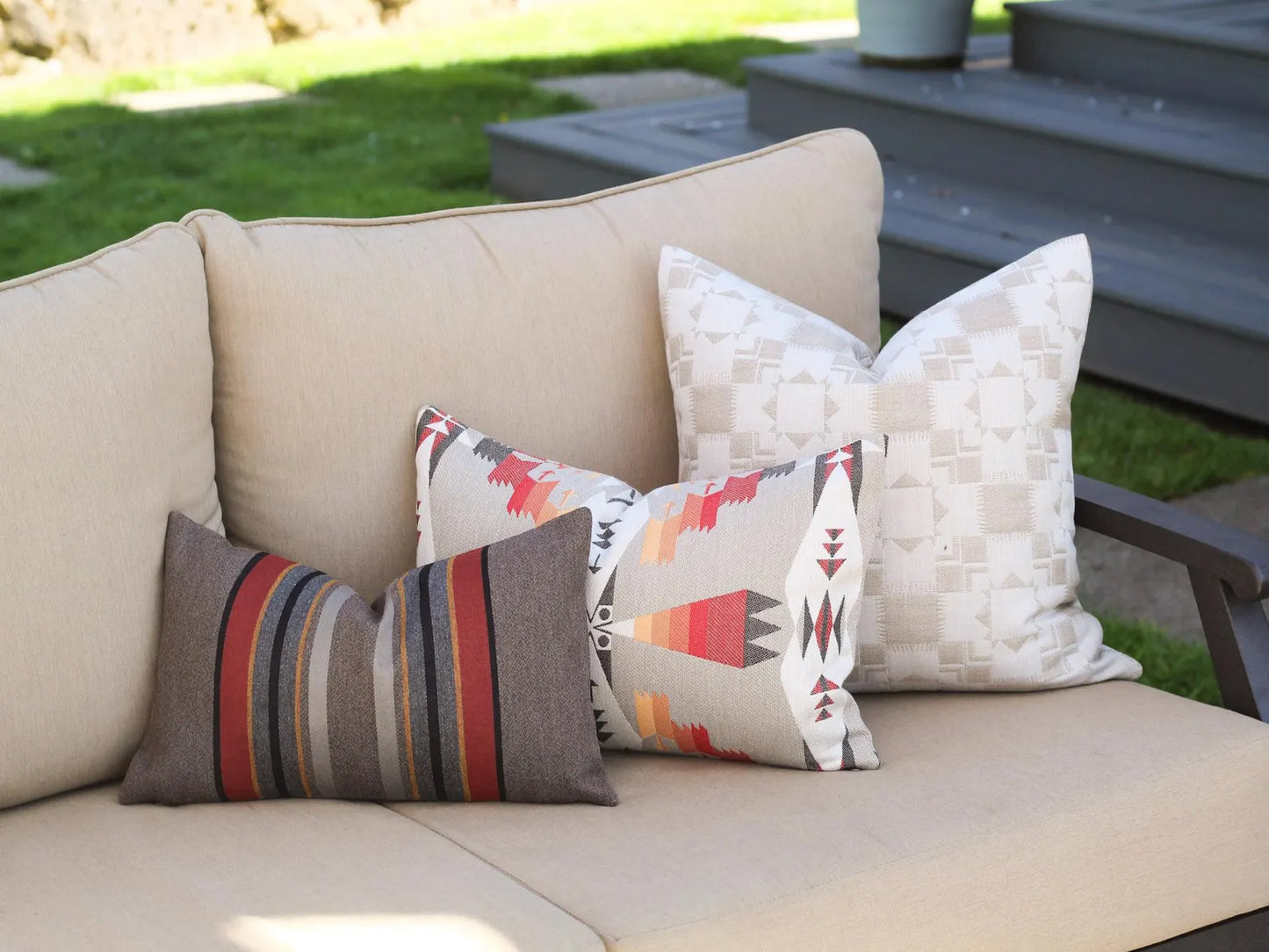 Outdoor pillows on a beige outdoor sofa with a garden background
