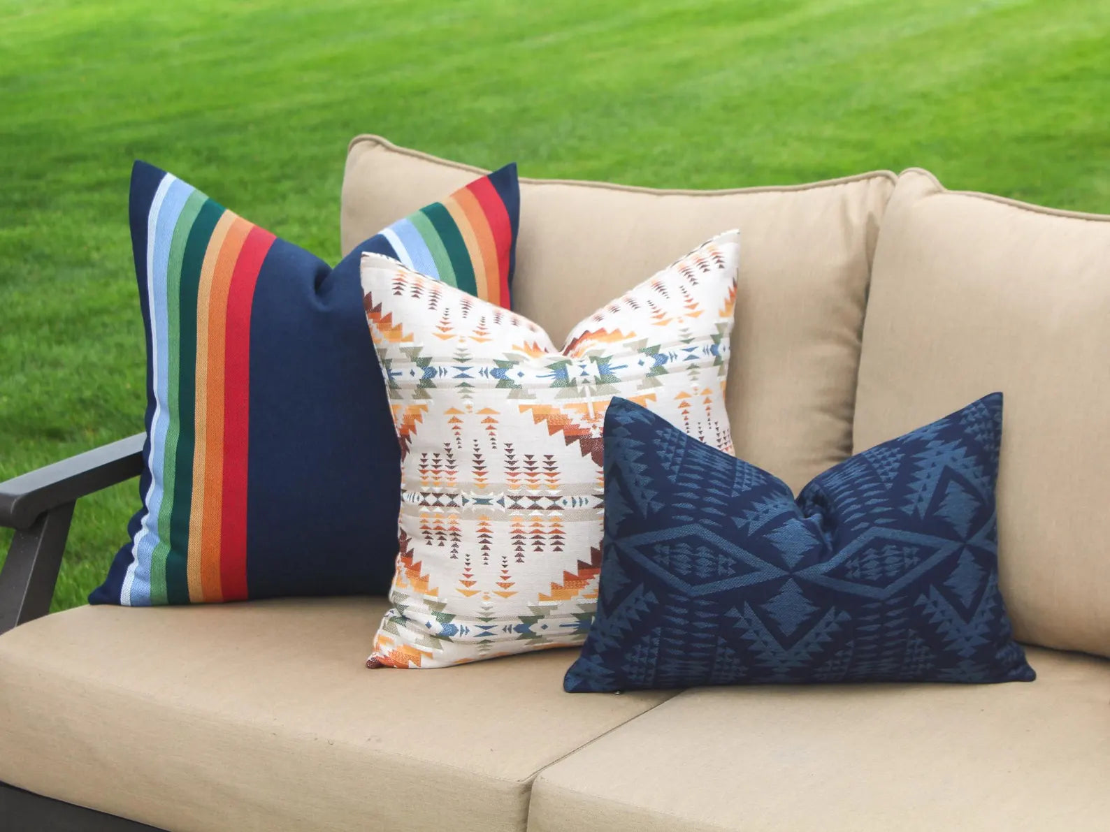 Colorful outdoor pillows on a beige sofa with a grassy background