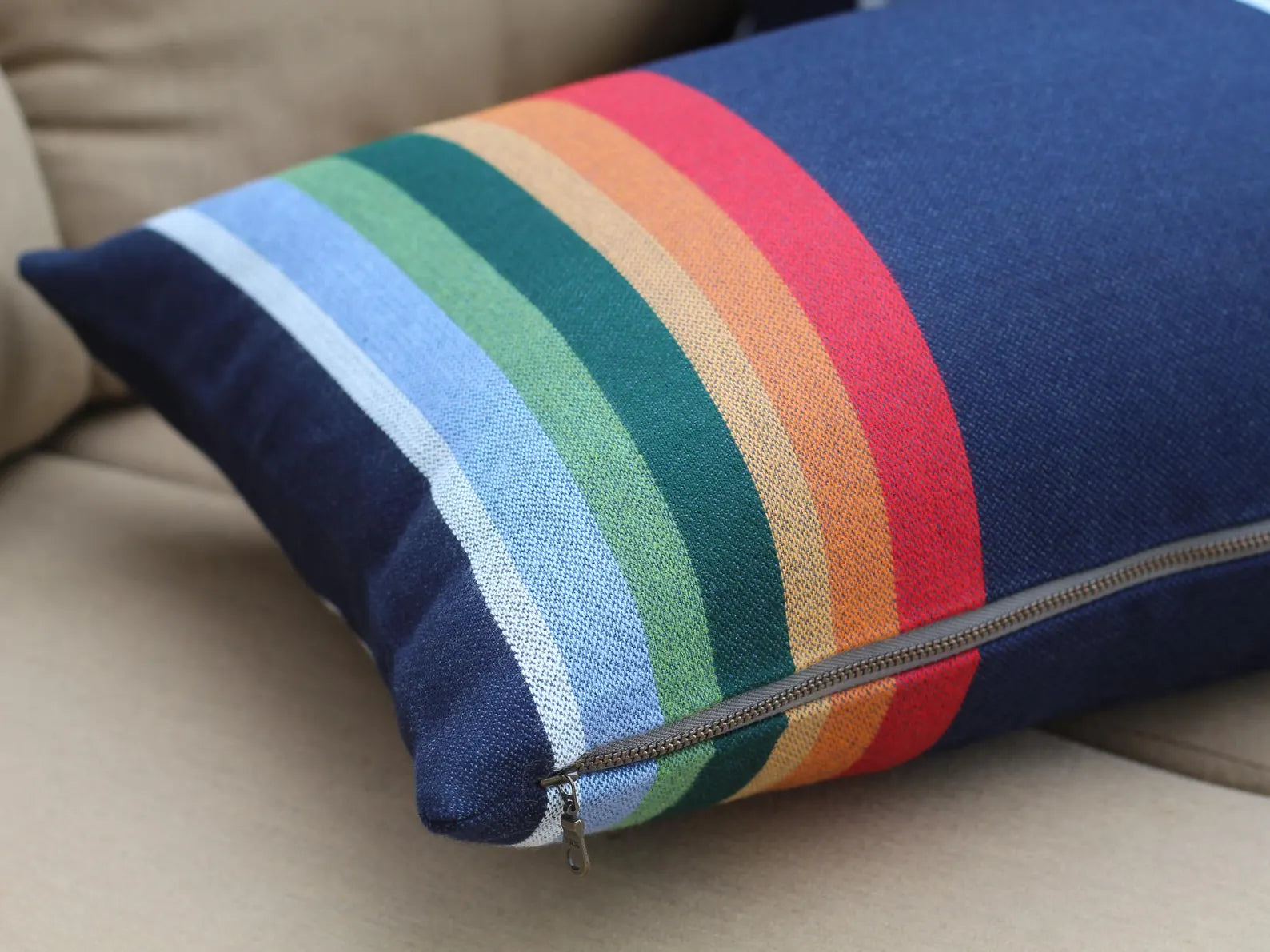 Colorful striped pillow with a zipper on a beige couch