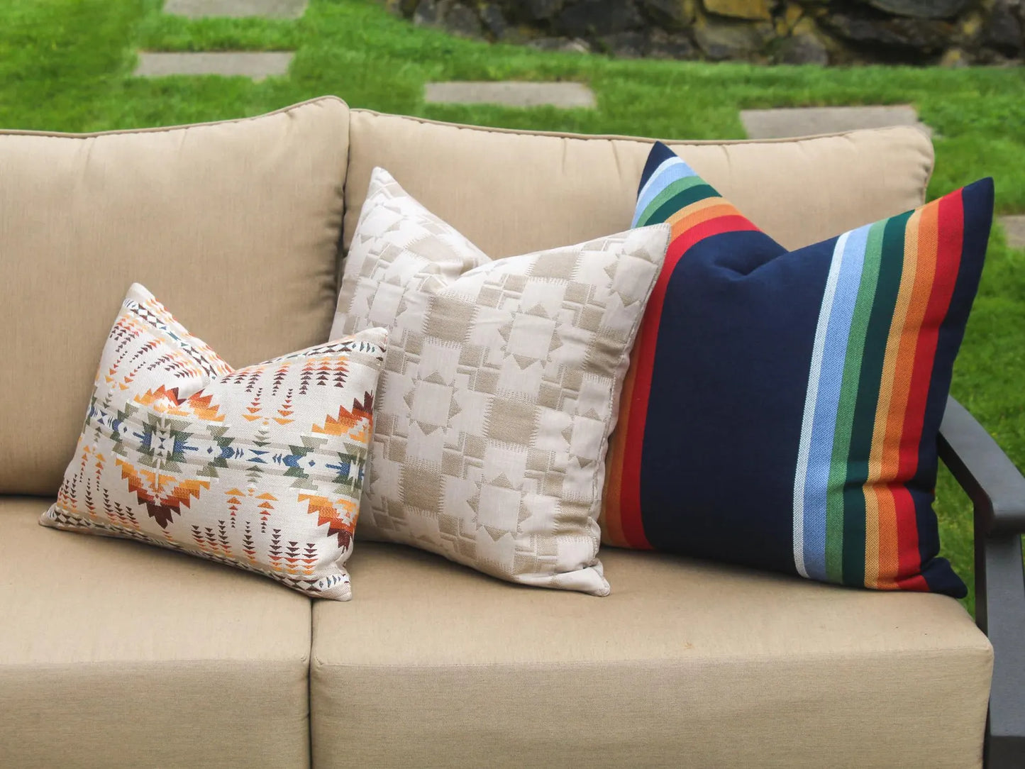 Beige outdoor sofa with patterned cushions on a grassy background