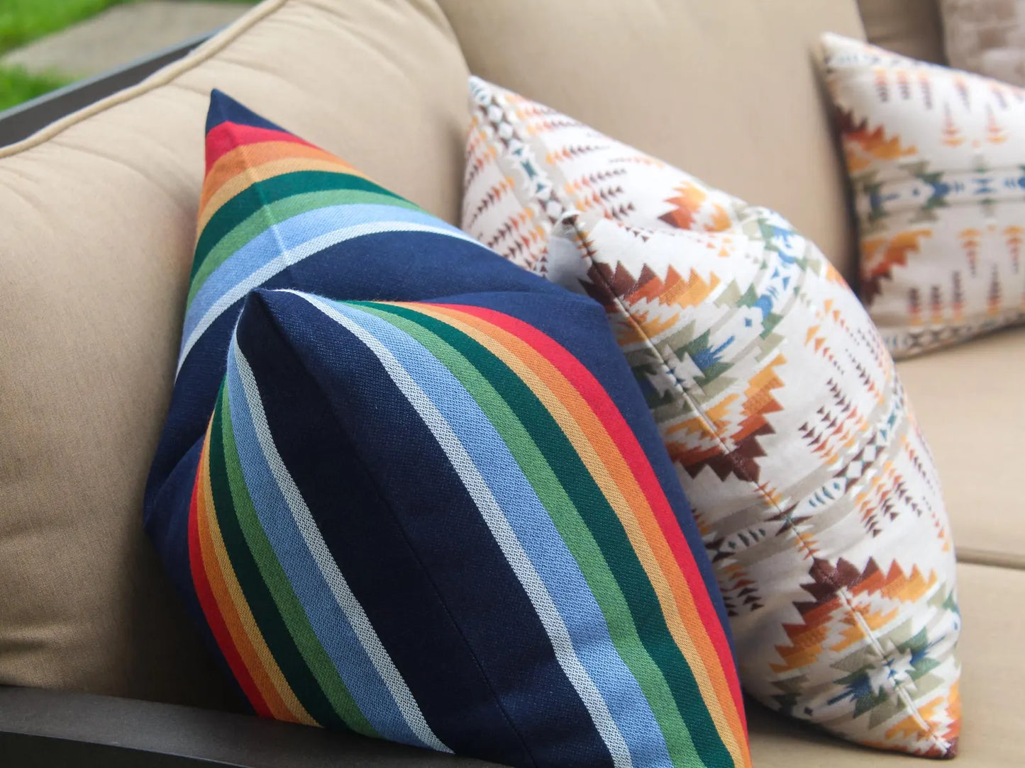 Colorful striped pillow on a beige couch with patterned pillows.